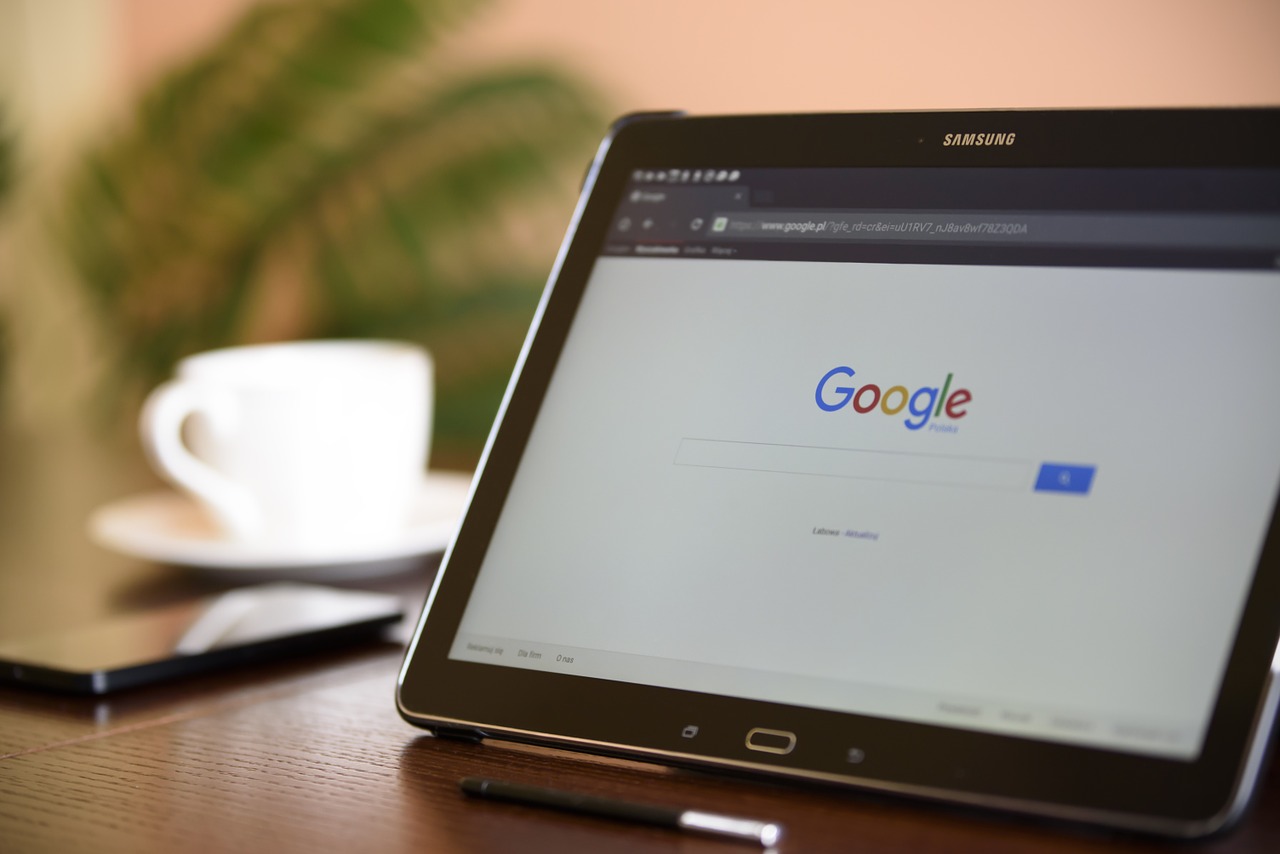 A tablet sitting on top a tabletop, with the Google search engine open on-screen.